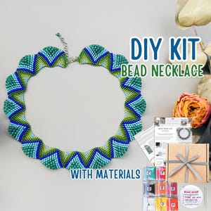 Könnte beinhalten: Ein DIY-Set für eine Perlenkette mit einer gewellten, zickzackförmigen Halskette in Grün-, Blau- und Gelbtönen. Das Set enthält eine gedruckte Anleitung, eine Pappschachtel mit grauem Band und kleine Plastiktüten mit verschiedenen Perlen.
