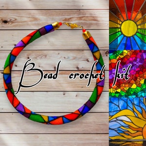 May include: A colourful beaded crochet necklace with a stained glass pattern. The necklace is made with small beads in shades of red, orange, yellow, green, blue, purple, and black. The necklace is on a wooden background with a close-up of the stained glass pattern.