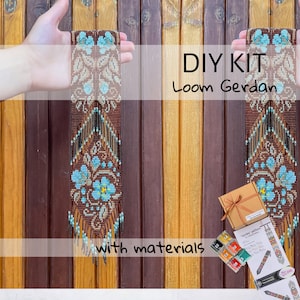 Op de afbeelding: Een doe-het-zelf-kit voor een weefgetouw gerdan, een kralenketting. De gerdan heeft een bloemenpatroon in bruine, beige en turquoise kralen. De kit bevat materialen en instructies. De tekst "DIY KIT Loom Gerdan with materials" is zichtbaar.