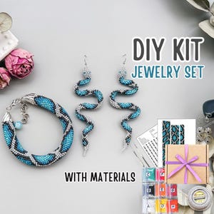May include: A DIY jewelry set featuring a beaded bracelet and snake-shaped earrings in shades of blue and silver. The set includes a gift box with a purple ribbon, vials of beads, and the text "DIY KIT JEWELRY SET WITH MATERIALS."