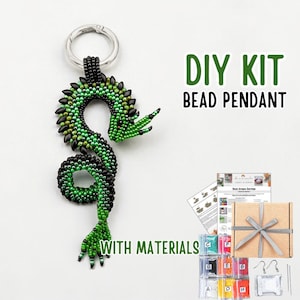 May include: A DIY bead pendant kit featuring a green and black beaded dragon pendant attached to a silver keychain. The kit includes materials, instructions, and a gift box. Text on the image reads "DIY KIT BEAD PENDANT WITH MATERIALS."