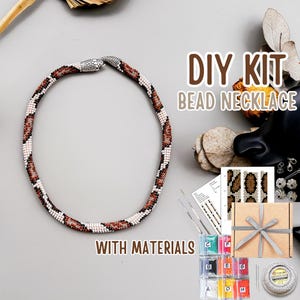 Puede incluir: Kit de collar de cuentas DIY con materiales. El collar tiene un diseño de serpiente con cuentas marrones, blancas y negras. El kit incluye cuentas, hilo e instrucciones. El texto "DIY KIT BEAD NECKLACE WITH MATERIALS" es visible.