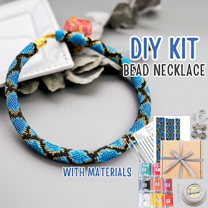 Op de afbeelding: DIY kralenketting kit met materialen. De ketting is blauw, zwart en goud gekleurd. De kit bevat kralen, draad, een geschenkdoos en andere benodigdheden. De tekst "DIY KIT BEAD NECKLACE WITH MATERIALS" is zichtbaar.