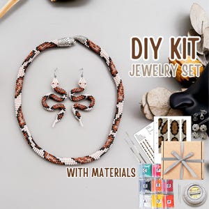 Puede incluir: Un kit de joyería DIY con un collar y pendientes de serpiente con cuentas. El conjunto incluye materiales, cuentas e instrucciones. El collar y los pendientes tienen un patrón marrón, blanco y negro. El texto "DIY KIT JEWELRY SET WITH MATERIALS" es visible.