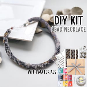 May include: A DIY bead necklace kit with materials. The kit includes a beaded necklace, beads, a gift box, and the text "DIY KIT BEAD NECKLACE WITH MATERIALS". The necklace is a mix of gray, yellow, and black beads.