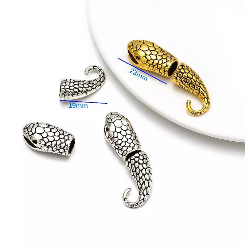 Peut inclure: Deux embouts de cordon en forme de serpent, l'un en argent et l'autre en or. Les embouts de cordon en argent mesurent 1,9 cm de long et l'embout de cordon en or mesure 2,3 cm de long.