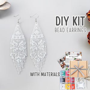 May include: A DIY kit for making beaded earrings. The image shows two white beaded earrings with a fringe design. The kit includes materials, instructions, and a gift box. Text on the image reads "DIY KIT BEAD EARRINGS WITH MATERIALS."