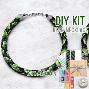 May include: A DIY bead necklace kit with materials. The necklace is green, black, and white with a snake-like pattern. The kit includes beads, thread, and instructions. The text "DIY KIT BEAD NECKLACE WITH MATERIALS" is visible.