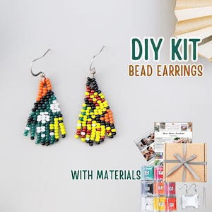 May include: DIY bead earring kit with materials. The image shows two beaded earrings with silver hooks. One earring is green, white, and orange. The other is yellow, black, and orange. The kit includes beads, instructions, and a gift box.