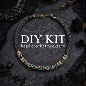 Op de afbeelding: Een DIY-kit voor een gehaakte kralenketting met een cirkelvormig touwontwerp. De ketting is voornamelijk zwart met een patroonsectie van turquoise, gouden en zwarte kralen. Het bevat bronzen eindkappen en een haaksluiting met blauwe accenten.