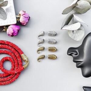 Peut inclure: Un collier de perles rouges avec des embouts en forme de serpent dor&eacute;s. L'image montre &eacute;galement des embouts en forme de serpent argent&eacute;s et dor&eacute;s.