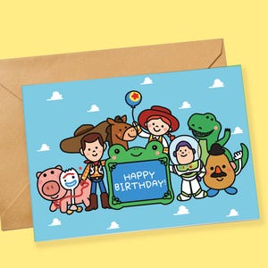 Può includere: Un biglietto d'auguri rettangolare con uno sfondo azzurro a motivi di nuvole bianche e un gruppo di personaggi dei cartoni animati. Una cornice verde a forma di rana al centro mostra il testo HAPPY BIRTHDAY! in lettere maiuscole bianche.