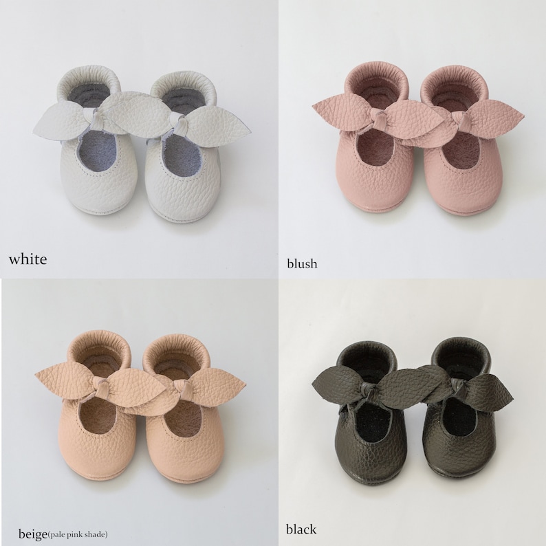 May include: Four pairs of leather baby shoes in different colours: white, blush, beige, and black. Each shoe has a bow on the top.