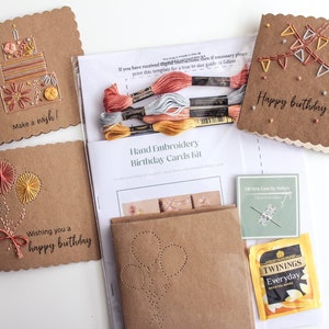 May include: A craft kit for making hand-embroidered birthday cards. The kit includes four pre-made cards with different designs, embroidery floss, a needle, and a tea bag. The cards feature designs of a birthday cake, balloons, bunting, and the text "Happy birthday to you".