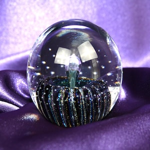 high quality and collectible art glass paper weight by Robert Eickholt featuring an iridescent center and rings of controlled bubbles