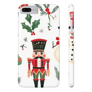 Puede incluir: Funda de teléfono blanca con un diseño navideño festivo. La funda presenta un cascanueces rojo y negro, hojas de acebo verdes, bayas rojas y un muñeco de nieve. Diseñado para un smartphone.