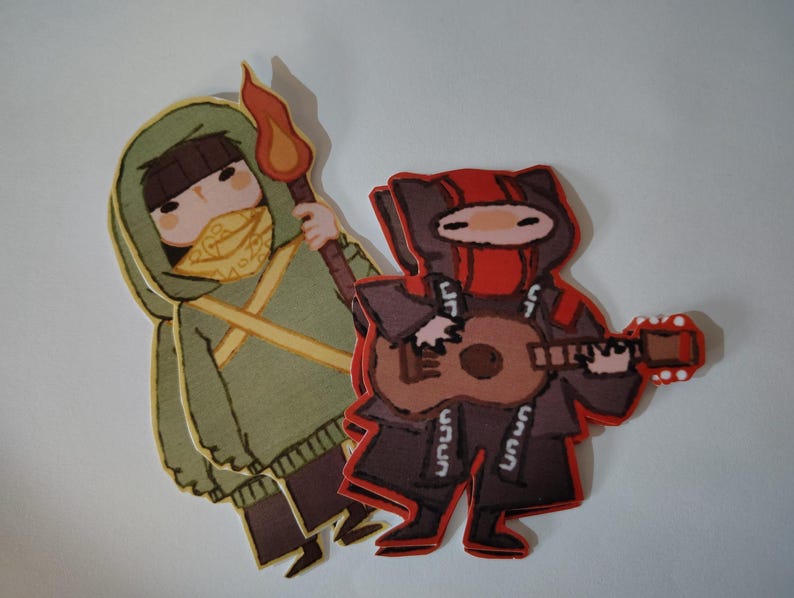 May include: Two cartoon figures are shown. One, in a green hooded cloak, holds a torch. The other, in a red and black outfit, plays a ukulele. Both figures have masked faces and are stylized with bold outlines.