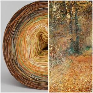 May include: A skein of yarn with a gradient of brown, orange, yellow, and green colours. The yarn is wound into a ball shape. The background is a blurry image of a forest path with fallen leaves.