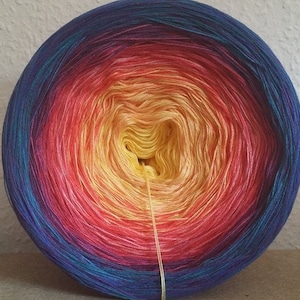 May include: A ball of yarn with a gradient of colours from blue to purple to red to yellow. The yarn is wound into a ball shape and is ready to be used for knitting or crocheting.
