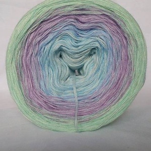 May include: A skein of yarn in a gradient of light green, blue, and purple colours. The yarn is wound into a ball shape.