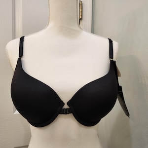 May include: A black bra with adjustable straps and a front closure. The bra is displayed on a mannequin, showcasing its smooth, seamless design. A tag hangs from the strap.