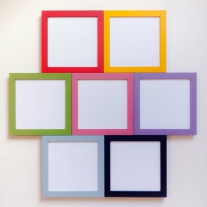 May include: Eight empty picture frames in various colours, including red, yellow, green, pink, purple, blue, and grey. The frames are arranged in a grid pattern on a white wall.