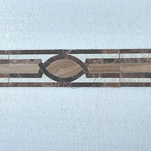 May include: Decorative tile border featuring a repeating pattern of oval and rectangular shapes in shades of brown, beige, and white. The border is framed by dark brown lines, creating a sophisticated design for home decor projects.