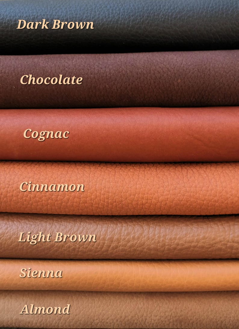 May include: A close-up of stacked leather swatches in various shades of brown. The colors range from dark brown to almond, with labels such as "Dark Brown", "Chocolate", "Cognac", "Cinnamon", "Light Brown", "Sienna", and "Almond".