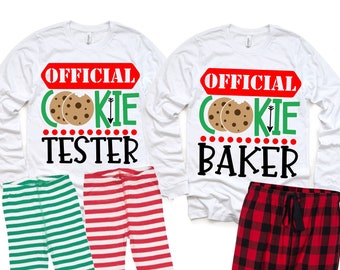 Puede incluir: Dos camisetas blancas de manga larga con el texto "OFFICIAL COOKIE TESTER" y "OFFICIAL COOKIE BAKER". Las camisetas se combinan con pantalones de pijama a rayas verdes y rojas y pantalones de pijama a cuadros rojos y negros.