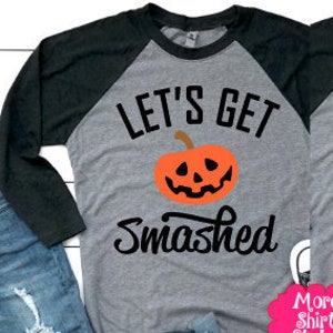 May include: Two gray and black raglan baseball shirts with long sleeves. The left shirt features an orange pumpkin graphic with the text "LET'S GET SMASHED". The right shirt features a white ghost graphic with the text "LET'S GET SHEET FACED".