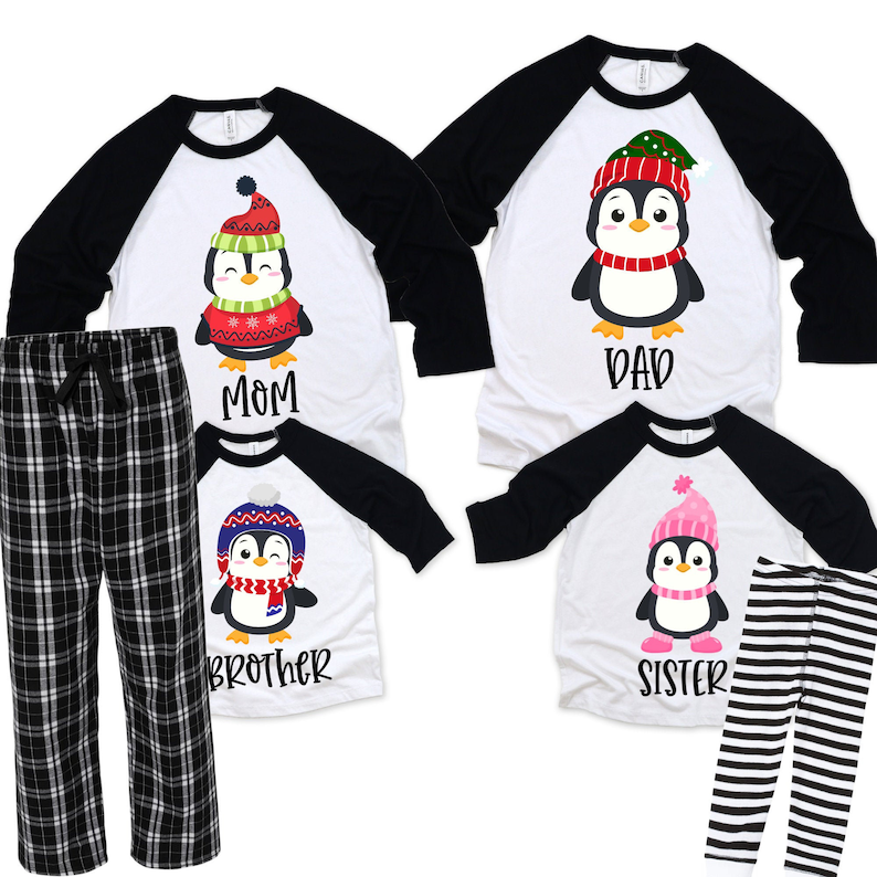 May include: Matching family pajamas featuring a penguin design. The shirts are white with black sleeves and a penguin wearing a hat and scarf. The pants are black and white plaid and black and white striped.