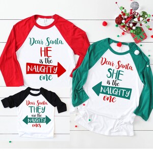 May include: Three white long-sleeved shirts with red, green, and black sleeves. The shirts have a Christmas theme with the text "Dear Santa, HE is the NAUGHTY one", "Dear Santa, SHE is the NAUGHTY one", and "Dear Santa, THEY are the NAUGHTY ones".