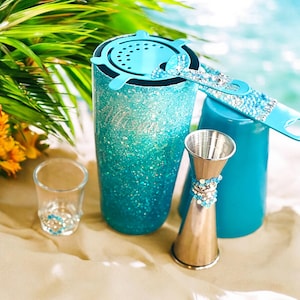 May include: A collection of barware items, including a glitter-covered tumbler, a shot glass, a jigger, and a bottle opener. The tumbler and bottle opener have crystal accents. The tumbler has the name "Allison" in silver script. The color scheme is turquoise and silver.