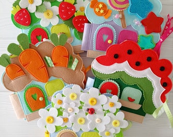 Könnte beinhalten: Eine Sammlung farbenfroher Filzhäuser mit verschiedenen dekorativen Elementen. Die Häuser zeigen Designs wie Erdbeeren, Karotten, Blumen und Süßigkeiten. Jedes Haus hat eine Tür und ist mit Knöpfen und Bändern verziert.