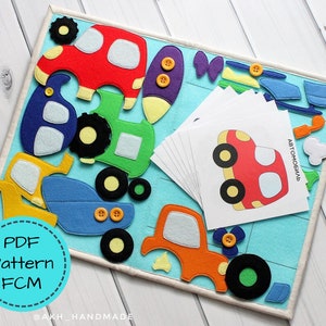 Peut inclure: Un tableau d'activités en feutre avec des formes de véhicules colorées et des cartes assorties. Le tableau présente une voiture rouge, un tracteur vert, un avion bleu et une voiture orange, avec des détails de boutons. Les cartes ont des illustrations de véhicules et du texte russe.