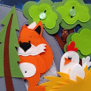 May include: A felt craft scene depicting a fox, a chicken in a nest, and an owl in a tree. The scene includes green trees with button accents and a grey mountain. The fox is orange and white, and the chicken is white with a red comb.