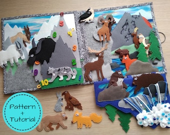 May include: A handmade felt quiet book with a mountain theme. The book features felt animals, mountains, trees, and numbers. The cover has the text "Pattern + Tutorial" in a blue circle. The book is designed for children.