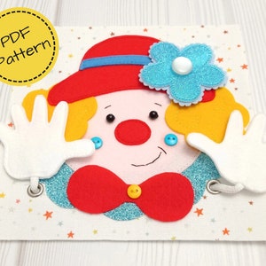 Può includere: Un viso da clown in feltro fatto a mano con cappello rosso, papillon e naso. Il clown ha capelli gialli, mani bianche e un fiore blu. Lo sfondo è un tessuto fantasia con stelle. Il testo "PDF Pattern" è in un cerchio giallo.