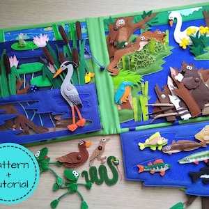 Puede incluir: Un libro tranquilo de fieltro hecho a mano con escenas acuáticas. El libro presenta una garza, ranas, peces y otros animales. La portada tiene el texto "Pattern + Tutorial" en un círculo turquesa. Las páginas son azules, verdes y marrones.