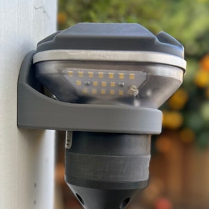 May include: A gray outdoor light fixture with a clear plastic cover and a row of white LED lights. The light is mounted on a white wall.