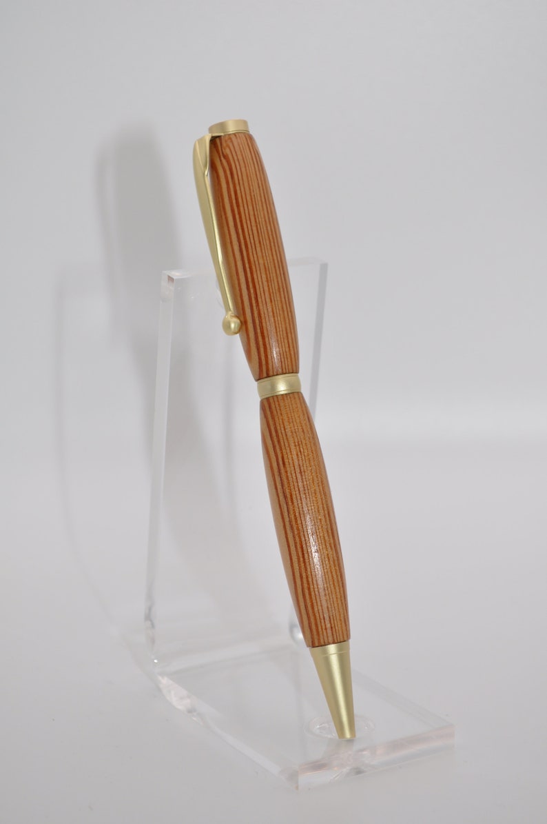May include: A wooden pen with gold accents. The pen has a striped wood pattern and a gold clip.