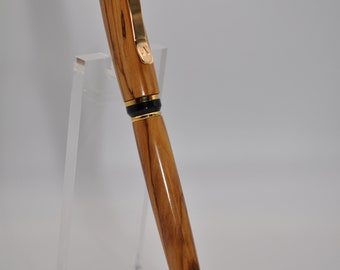 May include: A wooden pen with a gold trim and black accents. The pen is displayed on a clear acrylic stand.