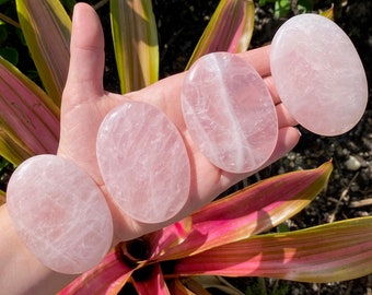 Può includere: Quattro pietre di quarzo rosa lisce, di forma ovale, di diverse dimensioni. Le pietre sono di colore rosa pallido con venature bianche che le attraversano.