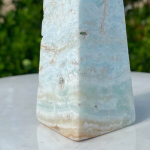 May include: A light blue and white celestite pyramid crystal with a smooth, polished surface.