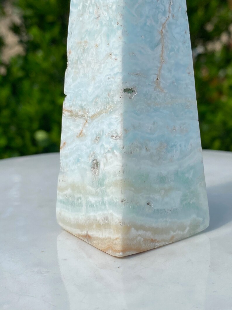 May include: A light blue and white celestite pyramid crystal with a smooth, polished surface.