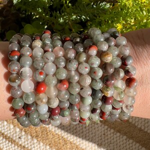 Pu&ograve; includere: Un set di braccialetti realizzati con perline di diaspro verde, rosso e bianco.