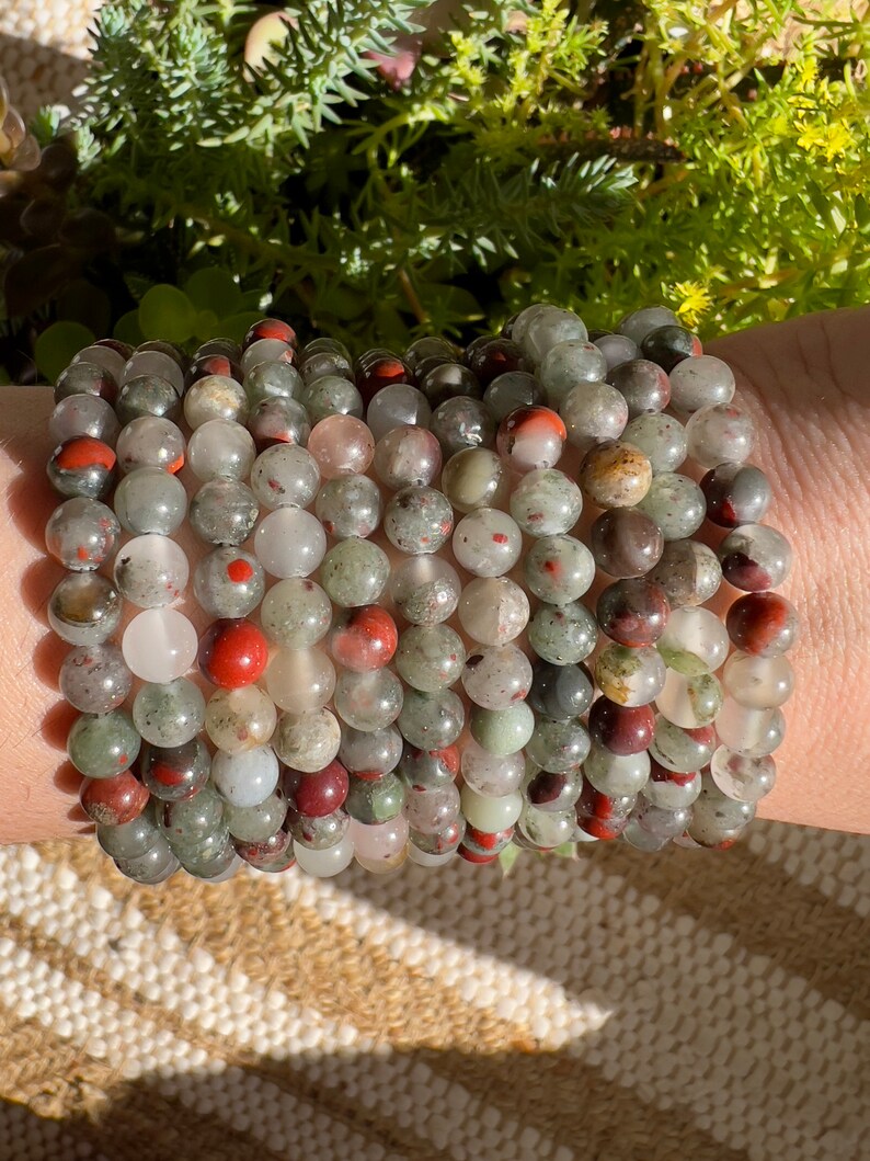 Pu&ograve; includere: Un set di braccialetti realizzati con perline di diaspro verde, rosso e bianco.