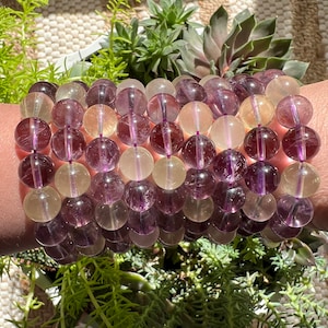 Puede incluir: Un brazalete de m&uacute;ltiples hilos hecho con cuentas de fluorita p&uacute;rpura y amarilla. Las cuentas son redondas y tienen un acabado liso y pulido.
