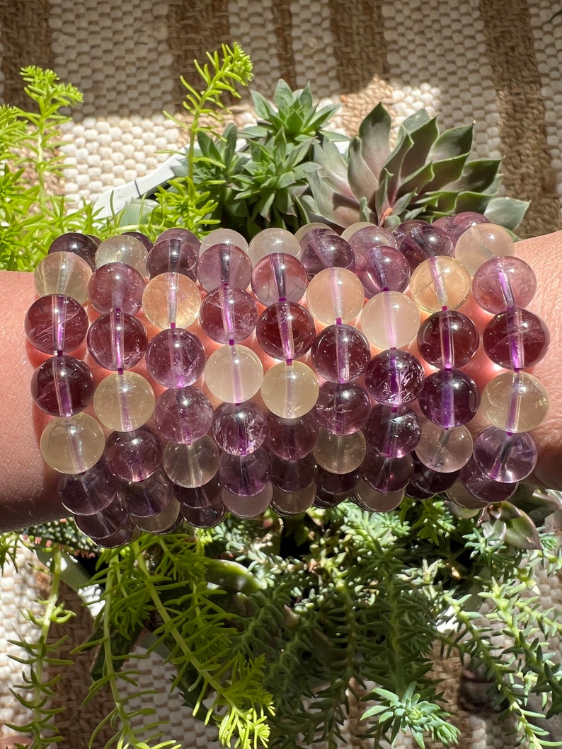 Puede incluir: Un brazalete de m&uacute;ltiples hilos hecho con cuentas de fluorita p&uacute;rpura y amarilla. Las cuentas son redondas y tienen un acabado liso y pulido.
