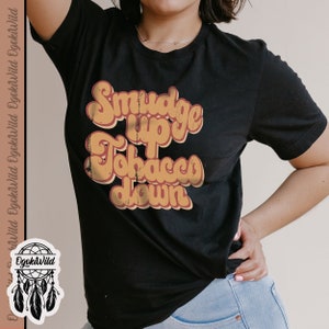 May include: A black t-shirt with a vintage-style graphic that reads "Smudge Up Tobacco Down". The graphic is in orange and brown with a distressed look.